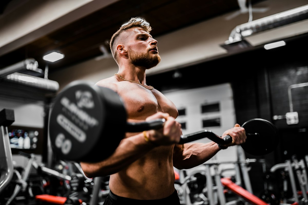 Dedicated natural lifter loading barbell plates in a gym for heavy progressive resistance training