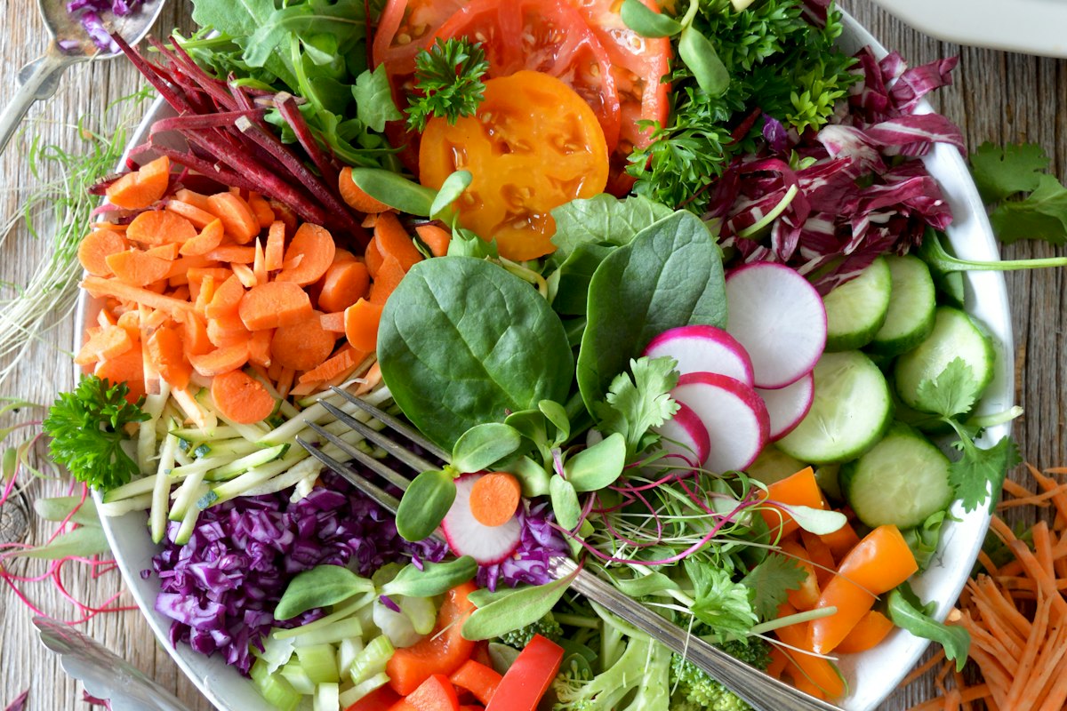 Fresh kidney-friendly plant-based bowl with leafy greens, vegetables, and olive oil dressing